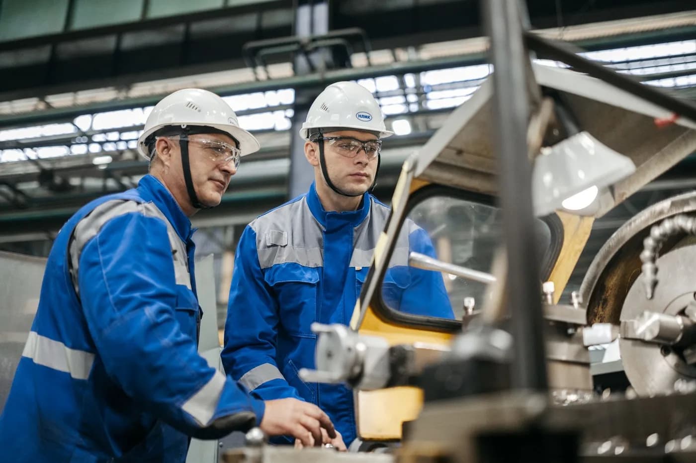 Industrial workers operating machinery on a factory floor.